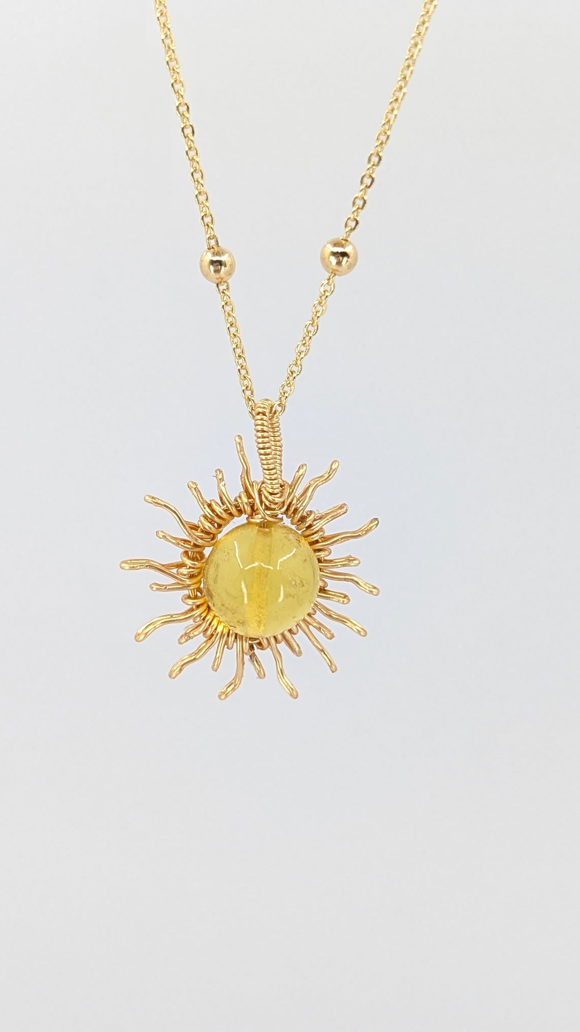 Handcrafted sun pendant necklace with light amber center stone on an adjustable gold-tone chain with bead detail