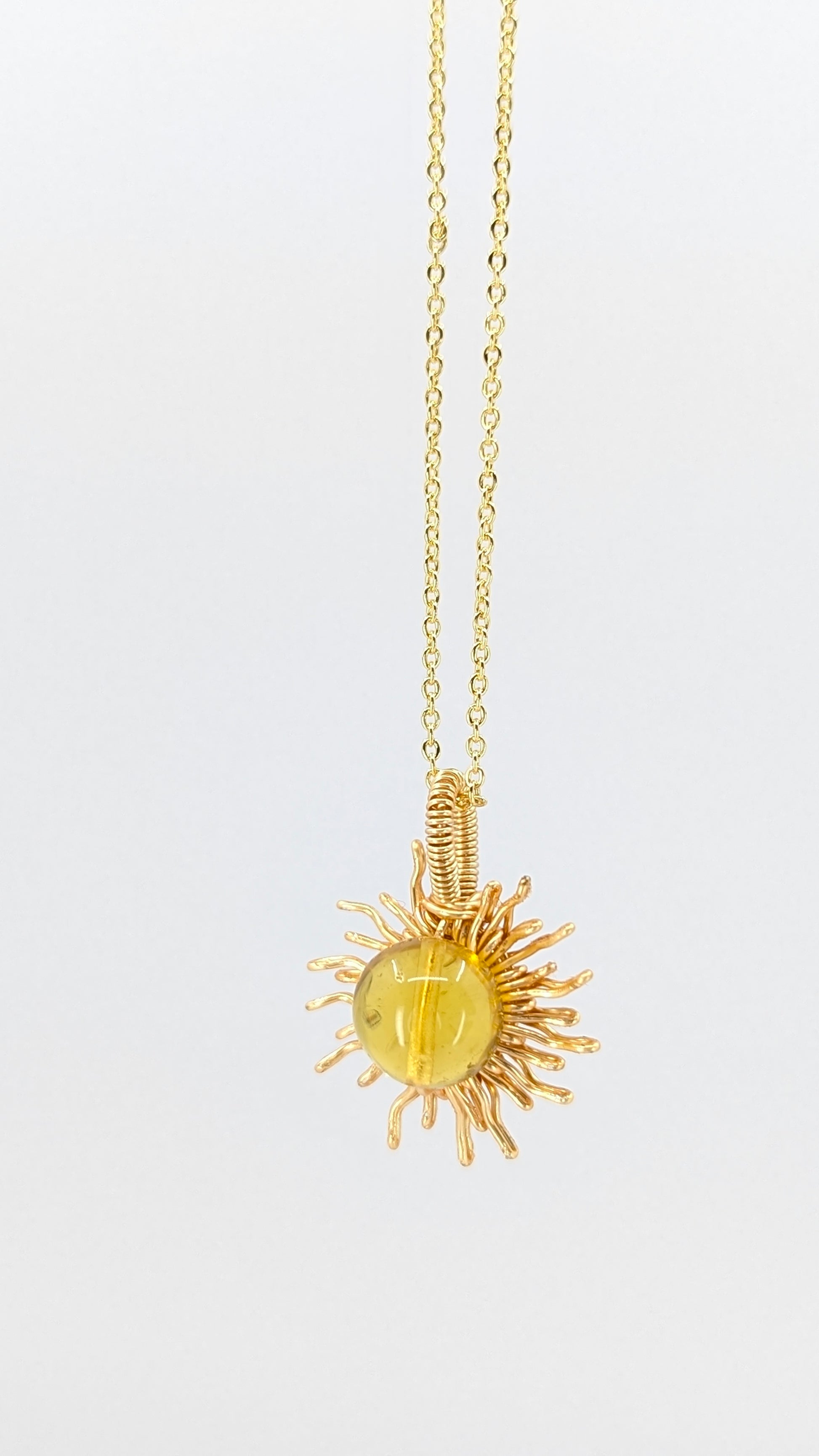 Handcrafted sun pendant necklace with very light amber rounded center stone on an adjustable gold-tone chain