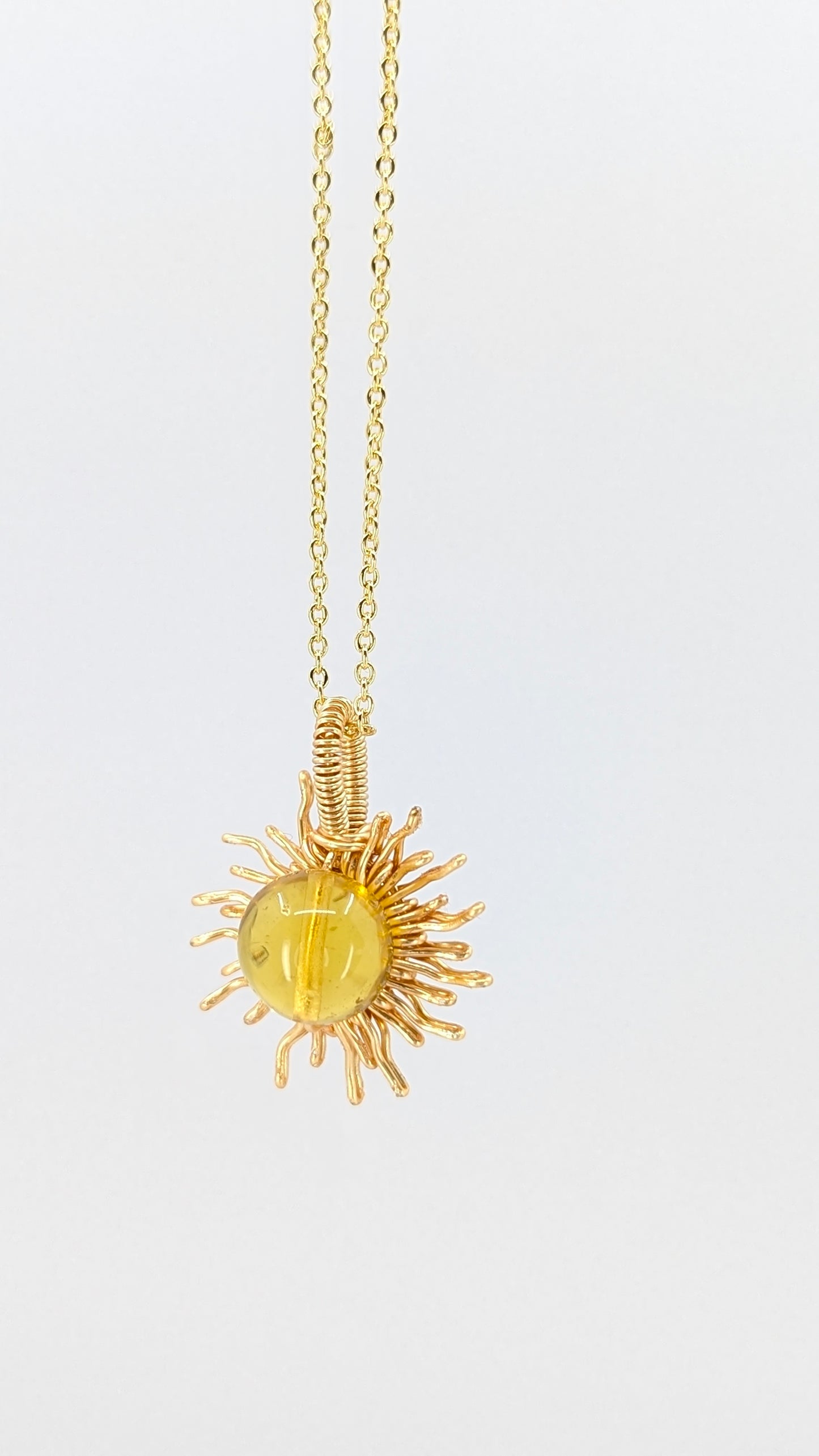 Handcrafted sun pendant necklace with very light amber rounded center stone on an adjustable gold-tone chain