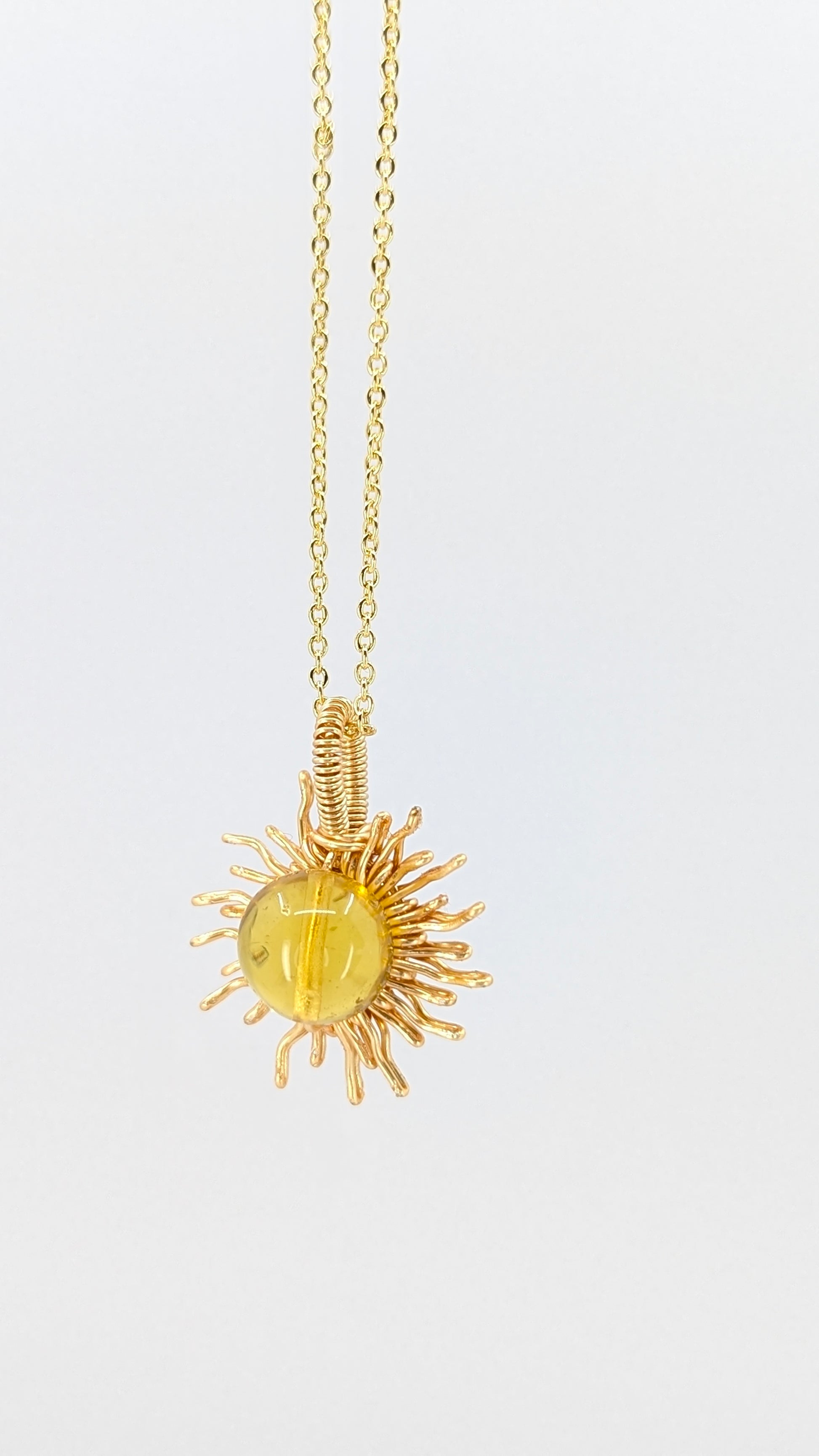 Handcrafted sun pendant necklace with very light amber rounded center stone on an adjustable gold-tone chain