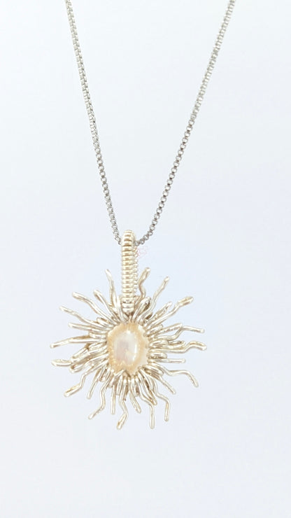 Back view of Necklace with a sun-shaped pendant featuring a freshwater pearl on a light gray background. The chain is silver-plated.