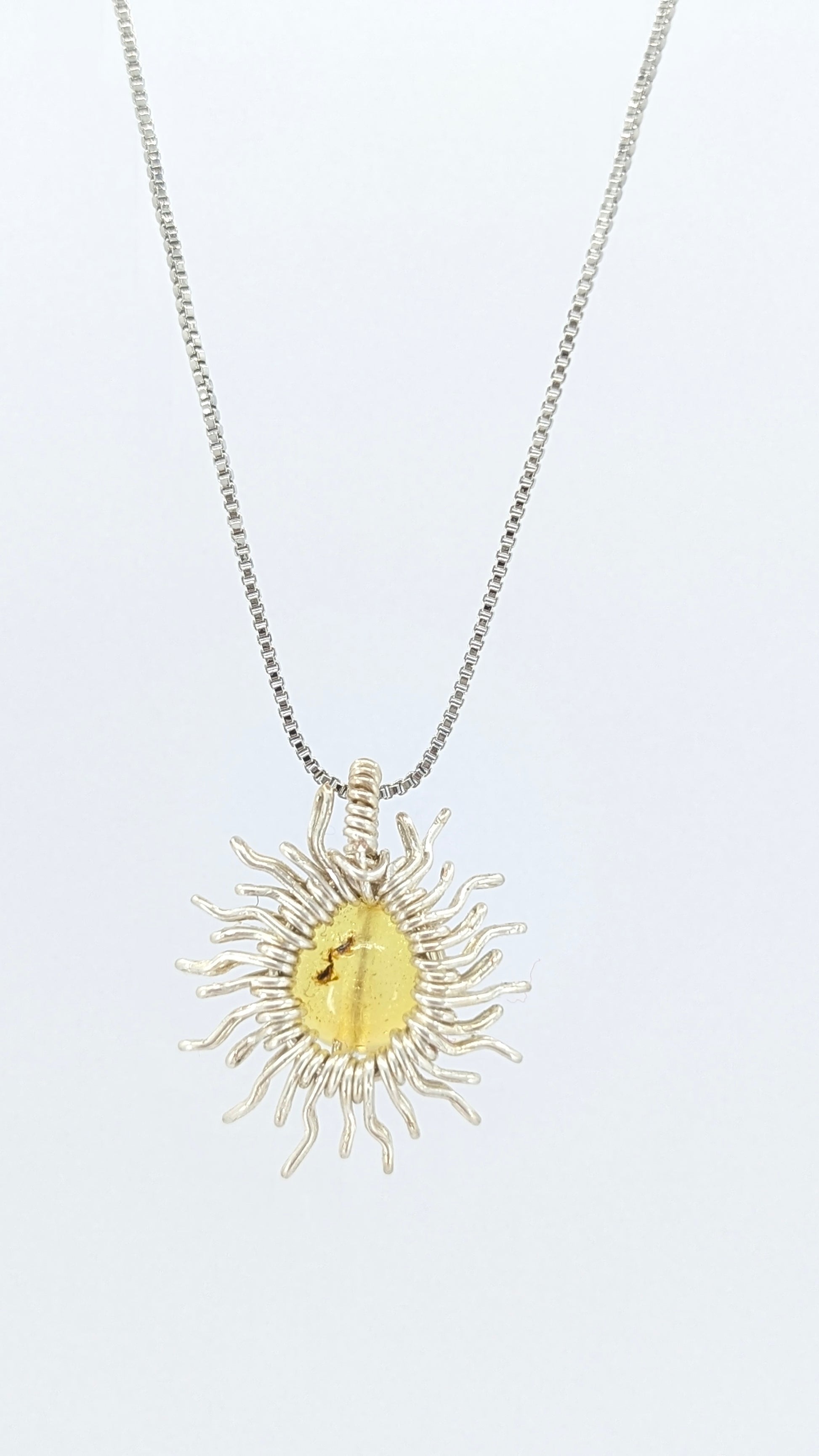 Handcrafted sun pendant necklace with rounded amber center stone on a silver-tone adjustable chain