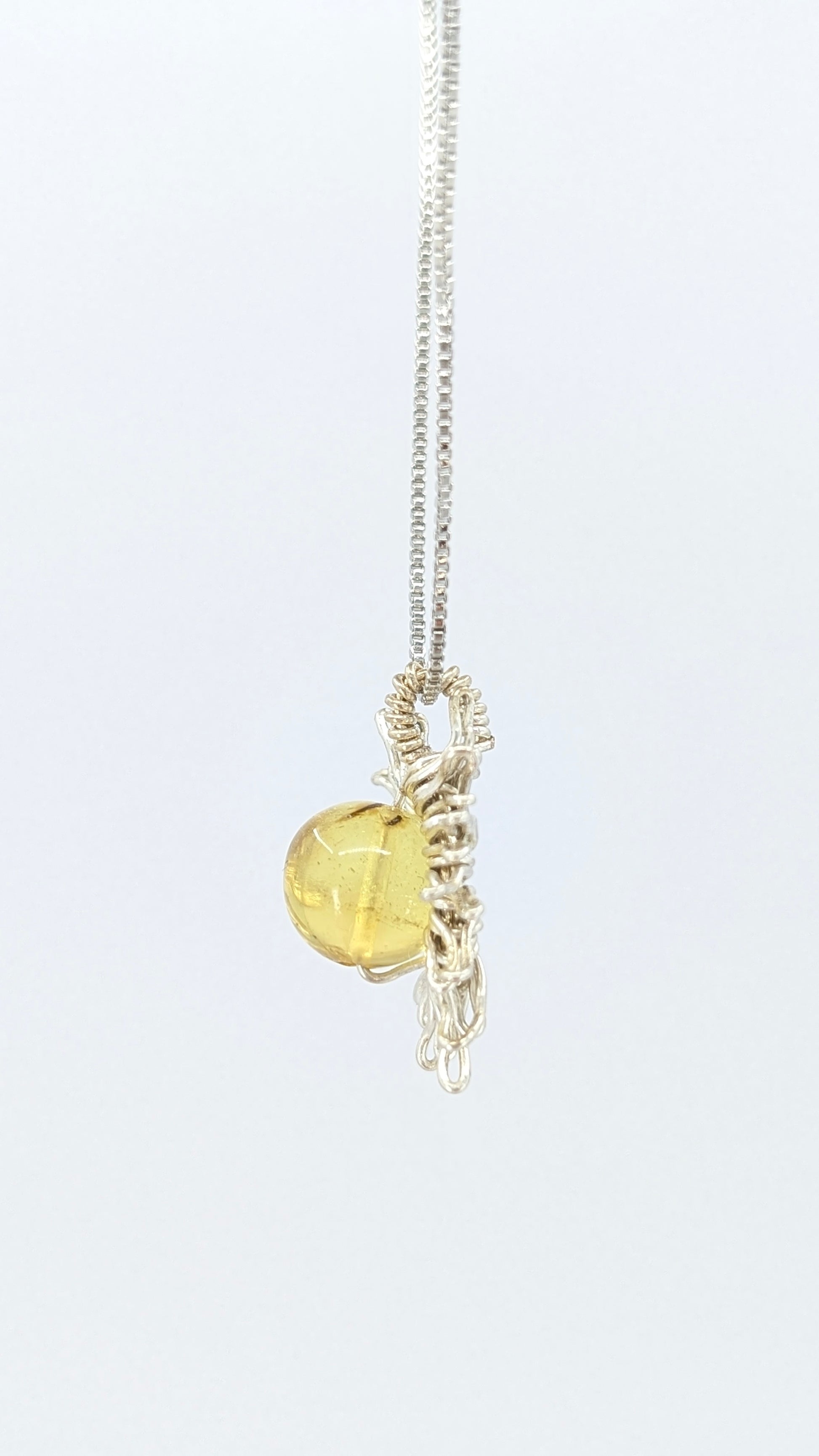 Handcrafted sun pendant necklace with rounded amber center stone on a silver-tone adjustable chain