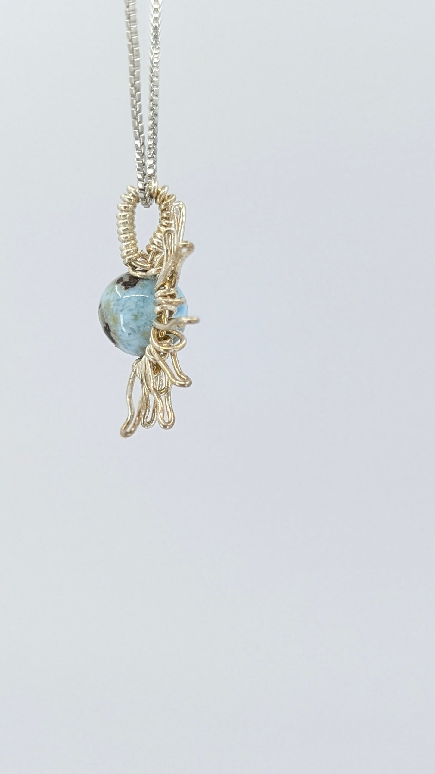 Lateral view of Handcrafted half sun pendant necklace with Larimar stone on a silver-tone adjustable chain