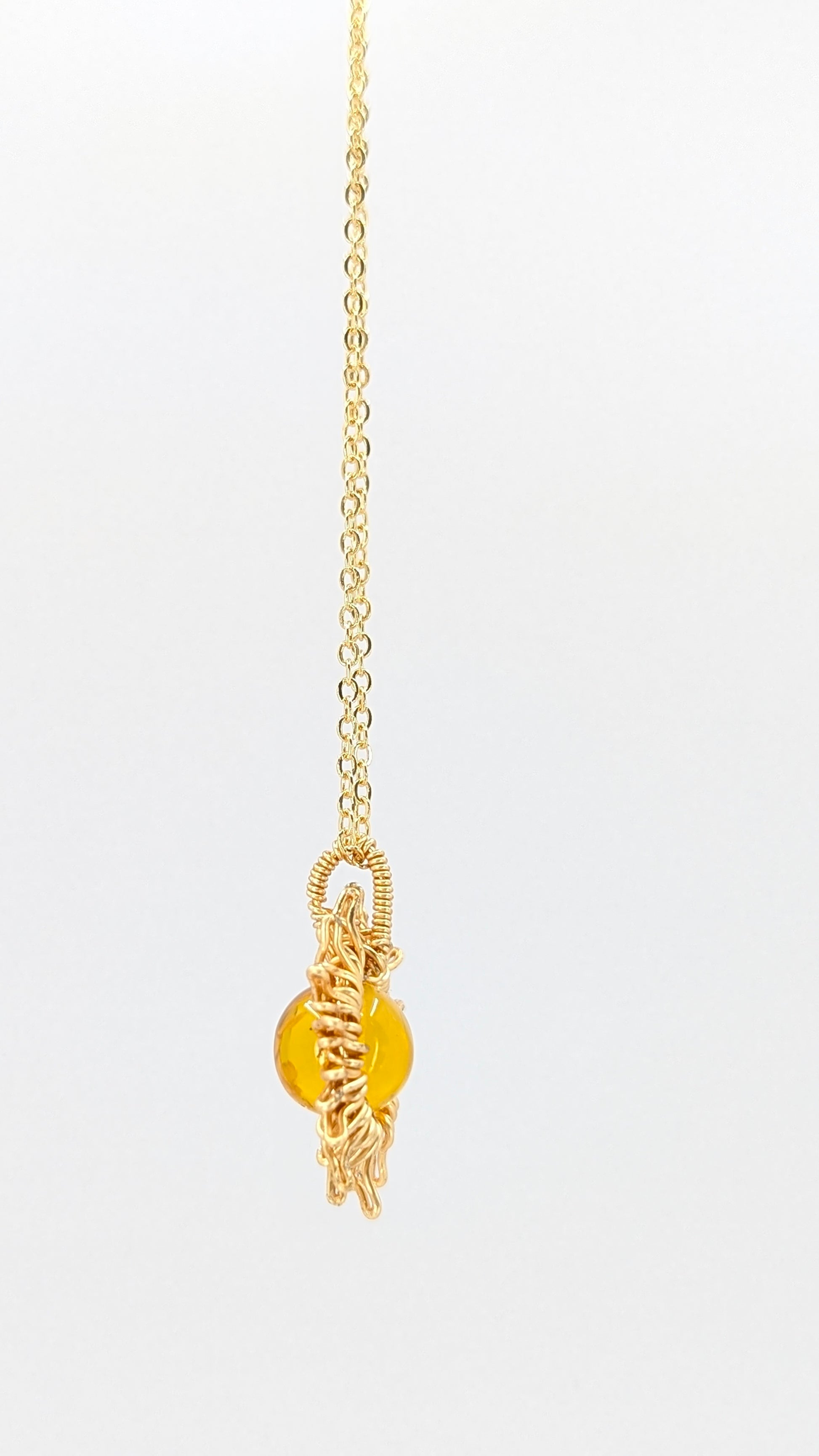 Handcrafted sun pendant necklace with warm rounded amber center stone on an adjustable gold-tone chain