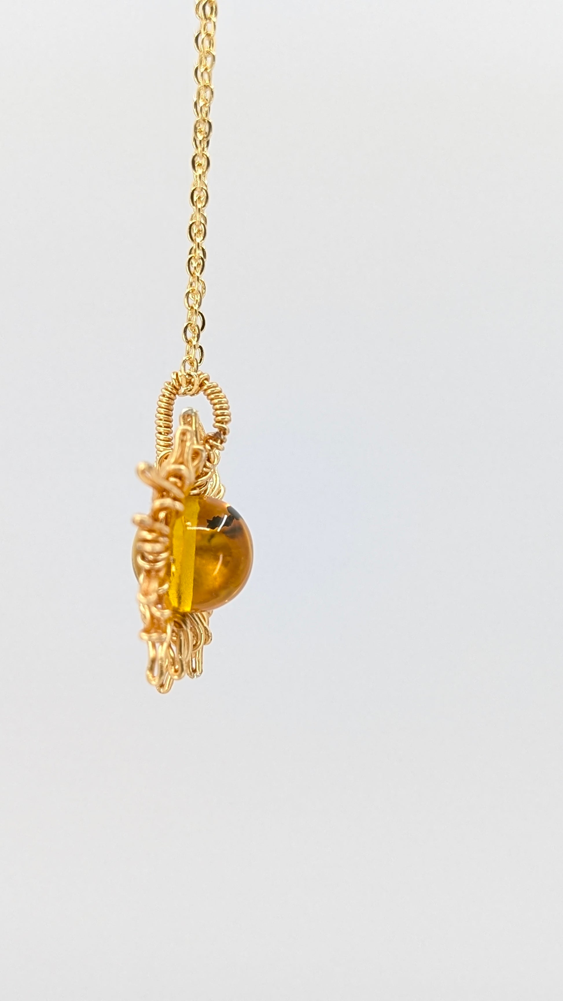 Handcrafted sun pendant necklace with warm rounded amber center stone on an adjustable gold-tone chain