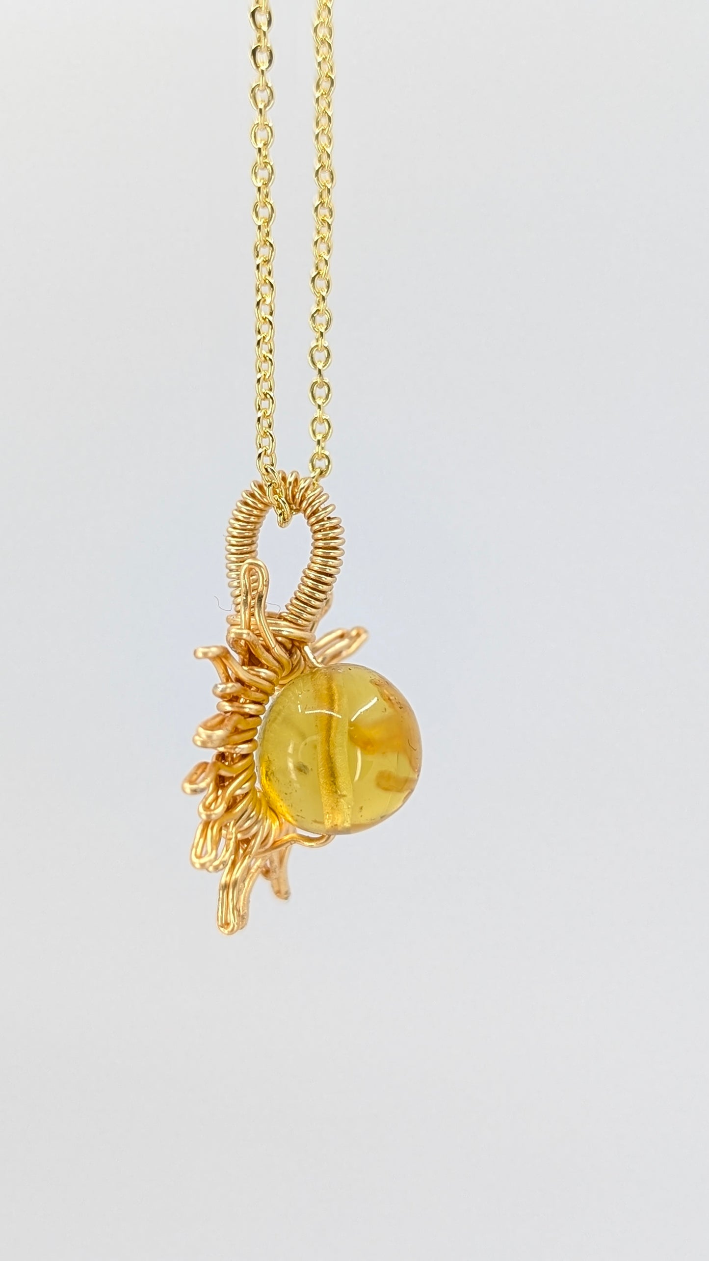 Handcrafted sun pendant necklace with very light amber rounded center stone on an adjustable gold-tone chain