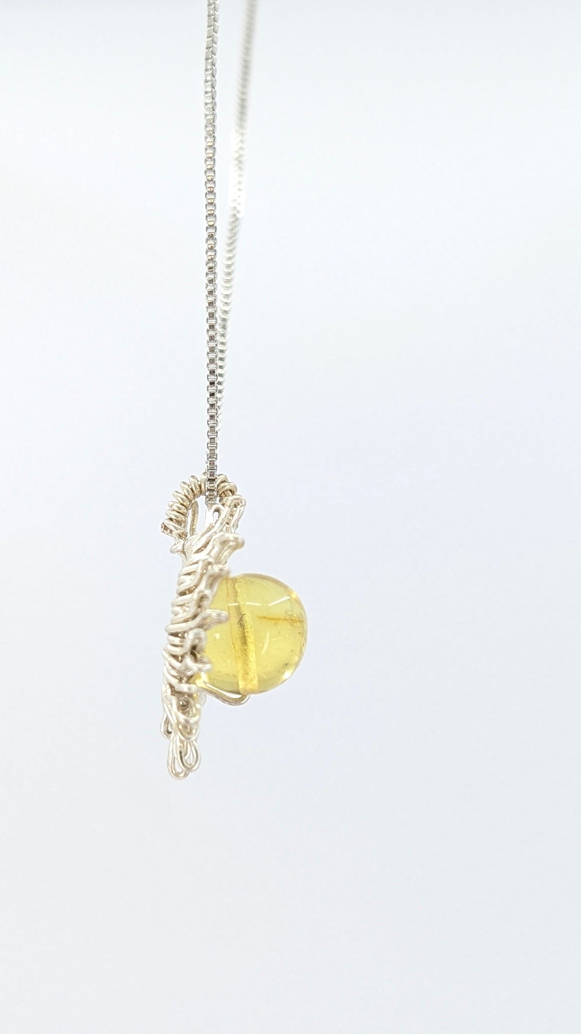 Handcrafted sun pendant necklace with rounded amber center stone on a silver-tone adjustable chain