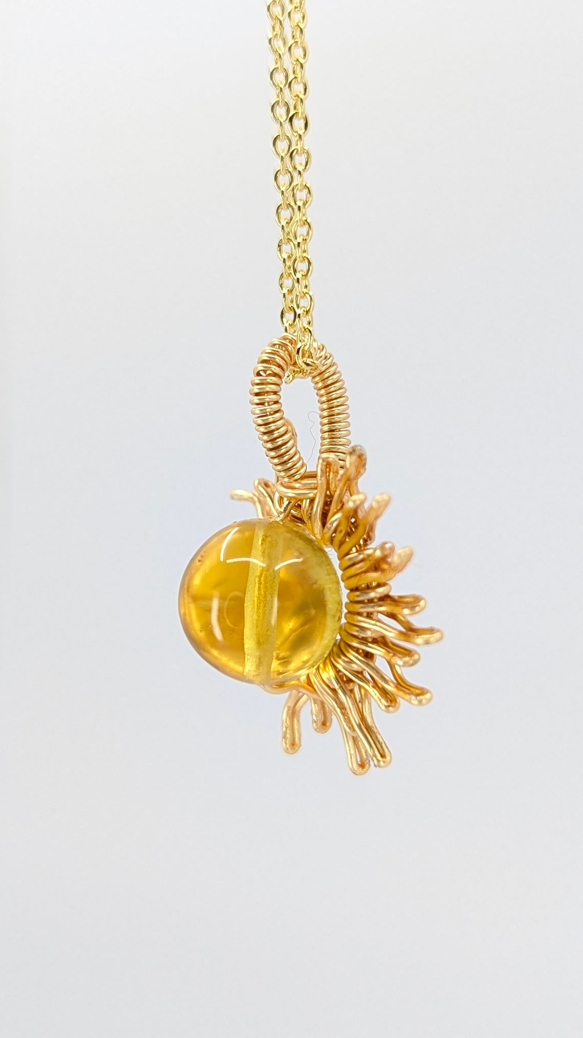 Handcrafted sun pendant necklace with very light amber rounded center stone on an adjustable gold-tone chain