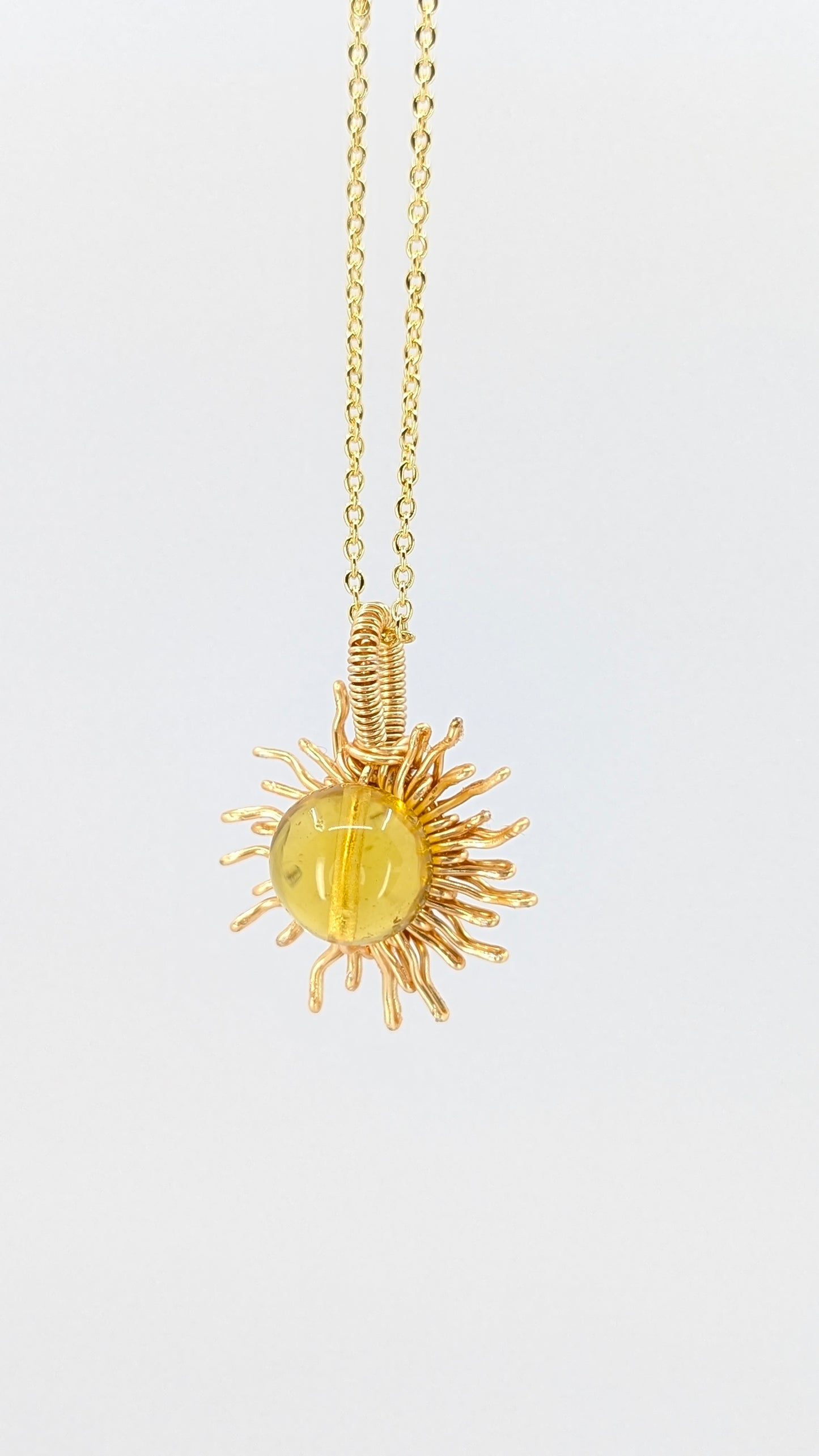 Handcrafted sun pendant necklace with very light amber rounded center stone on an adjustable gold-tone chain