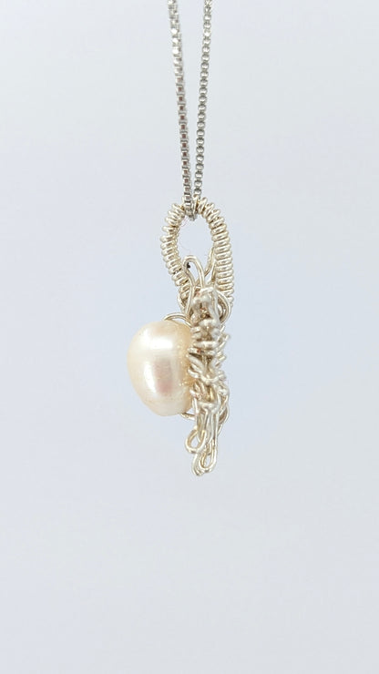 Another lateral  view of Necklace with a sun-shaped pendant featuring a freshwater pearl on a light gray background.