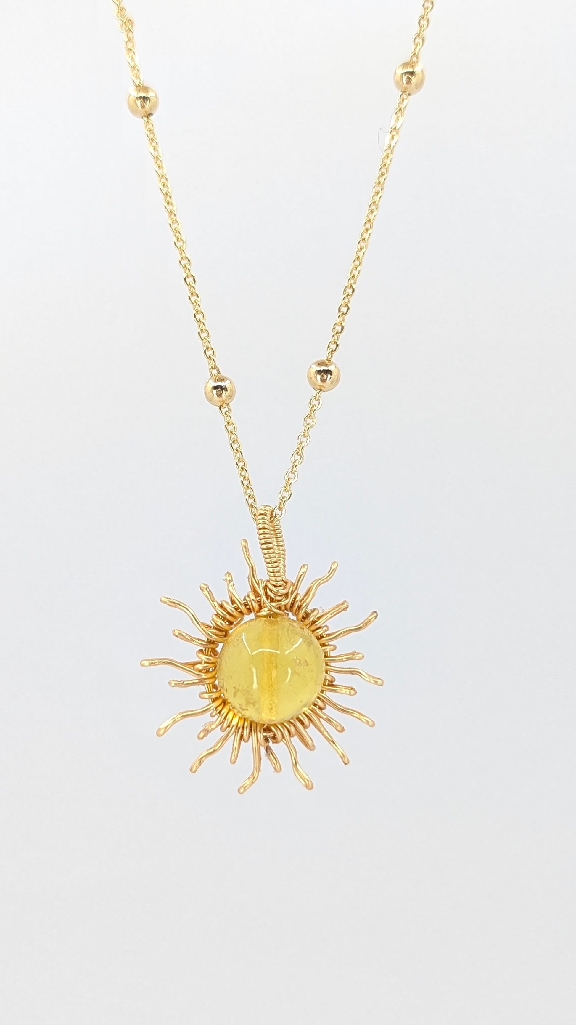Handcrafted sun pendant necklace with light amber center stone on an adjustable gold-tone chain with bead detail