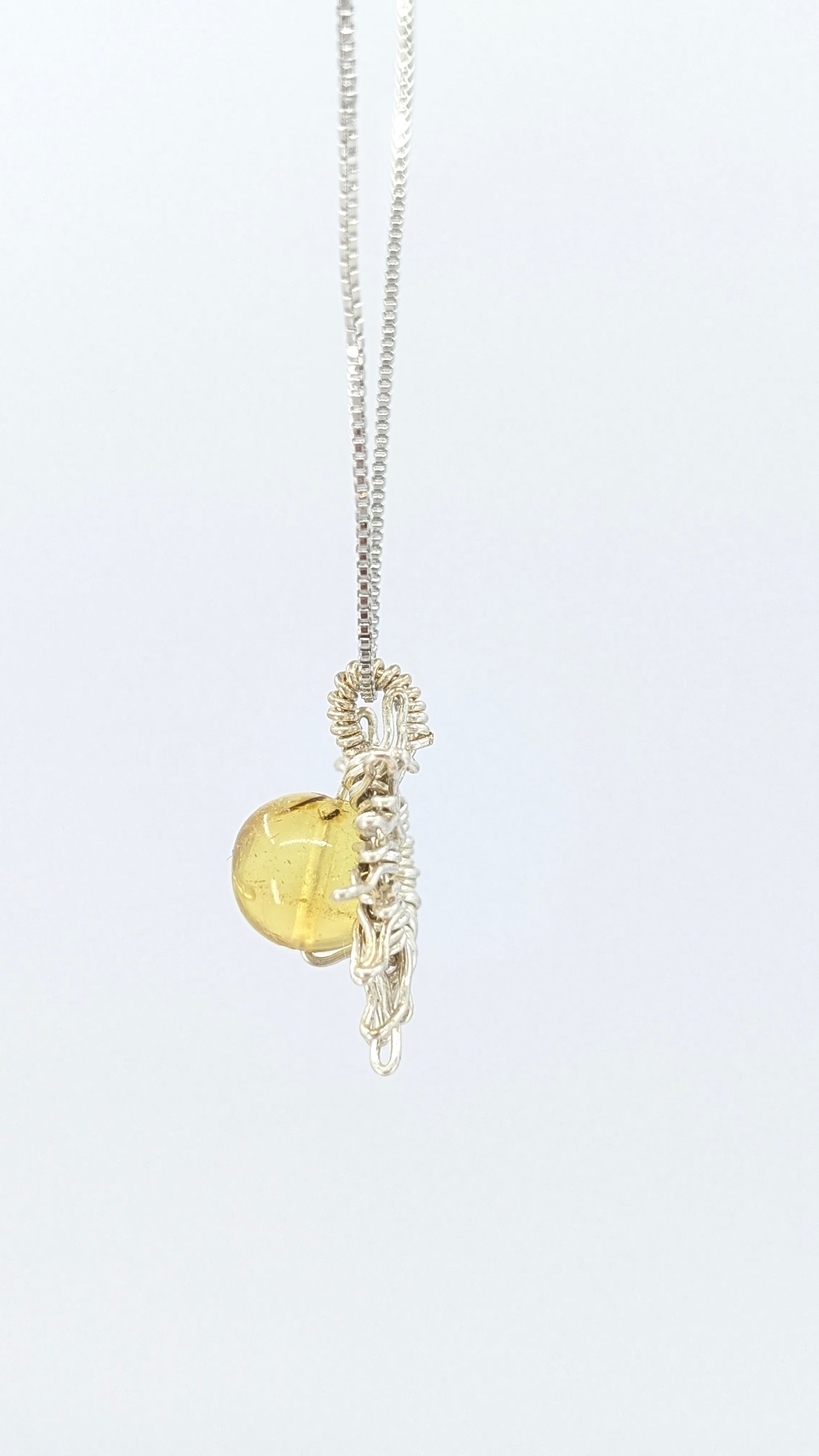 Handcrafted sun pendant necklace with rounded amber center stone on a silver-tone adjustable chain