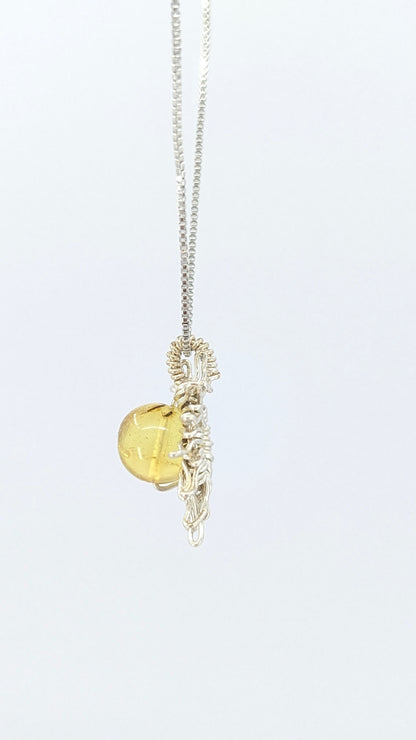 Handcrafted sun pendant necklace with rounded amber center stone on a silver-tone adjustable chain
